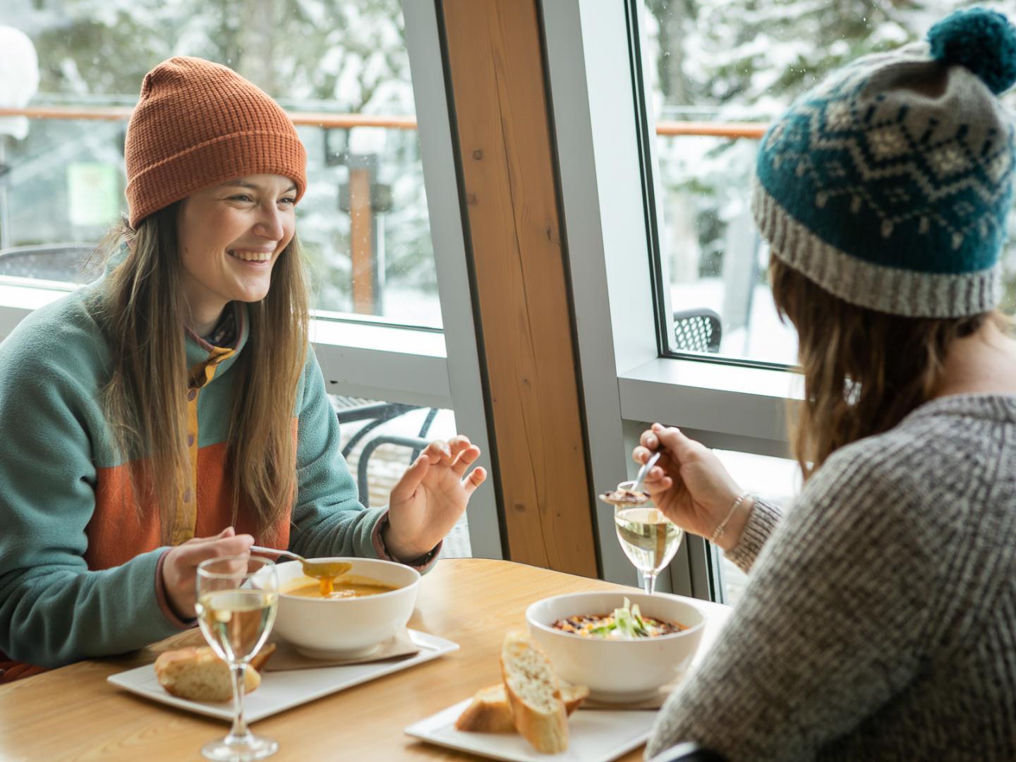 a pair of women eating soup in ski day lodge