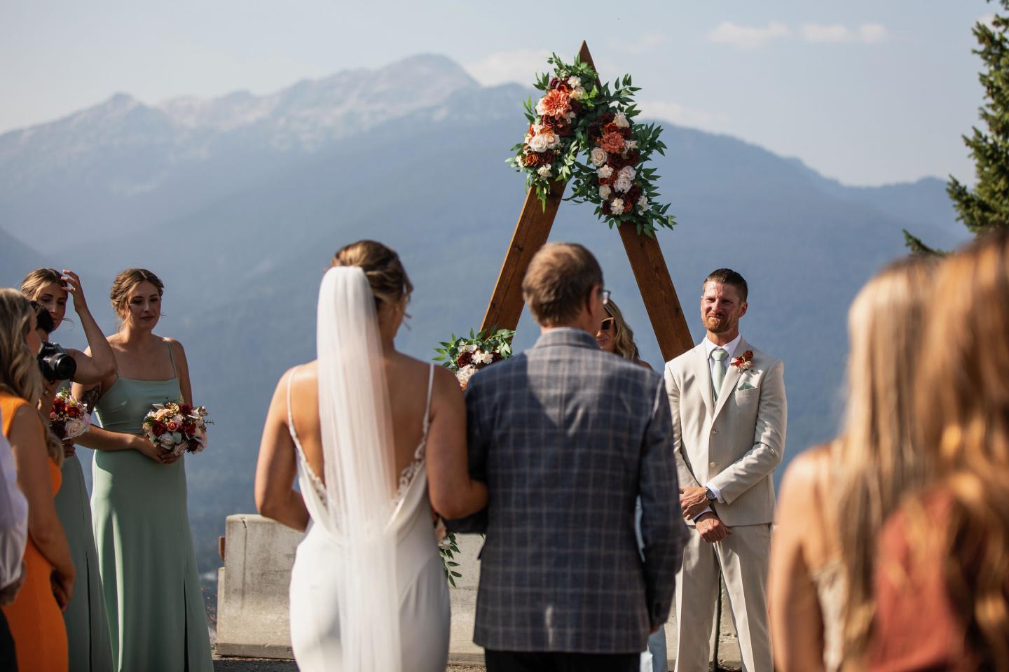 father giving away daughter at outdoor ceremony with mountain in the background