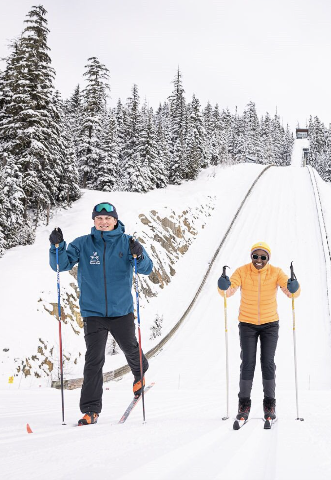 Whistler Olympic Park in the Callaghan Valley -Two skiers on a snowy slope, surrounded by tall, snow-covered trees.