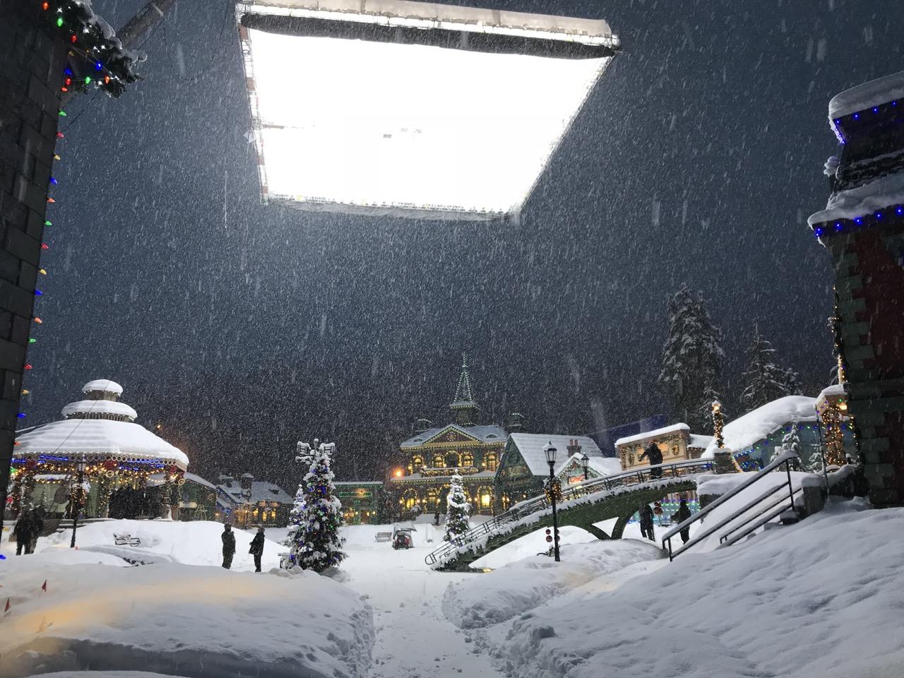 Snow-covered village set under large studio light at night.