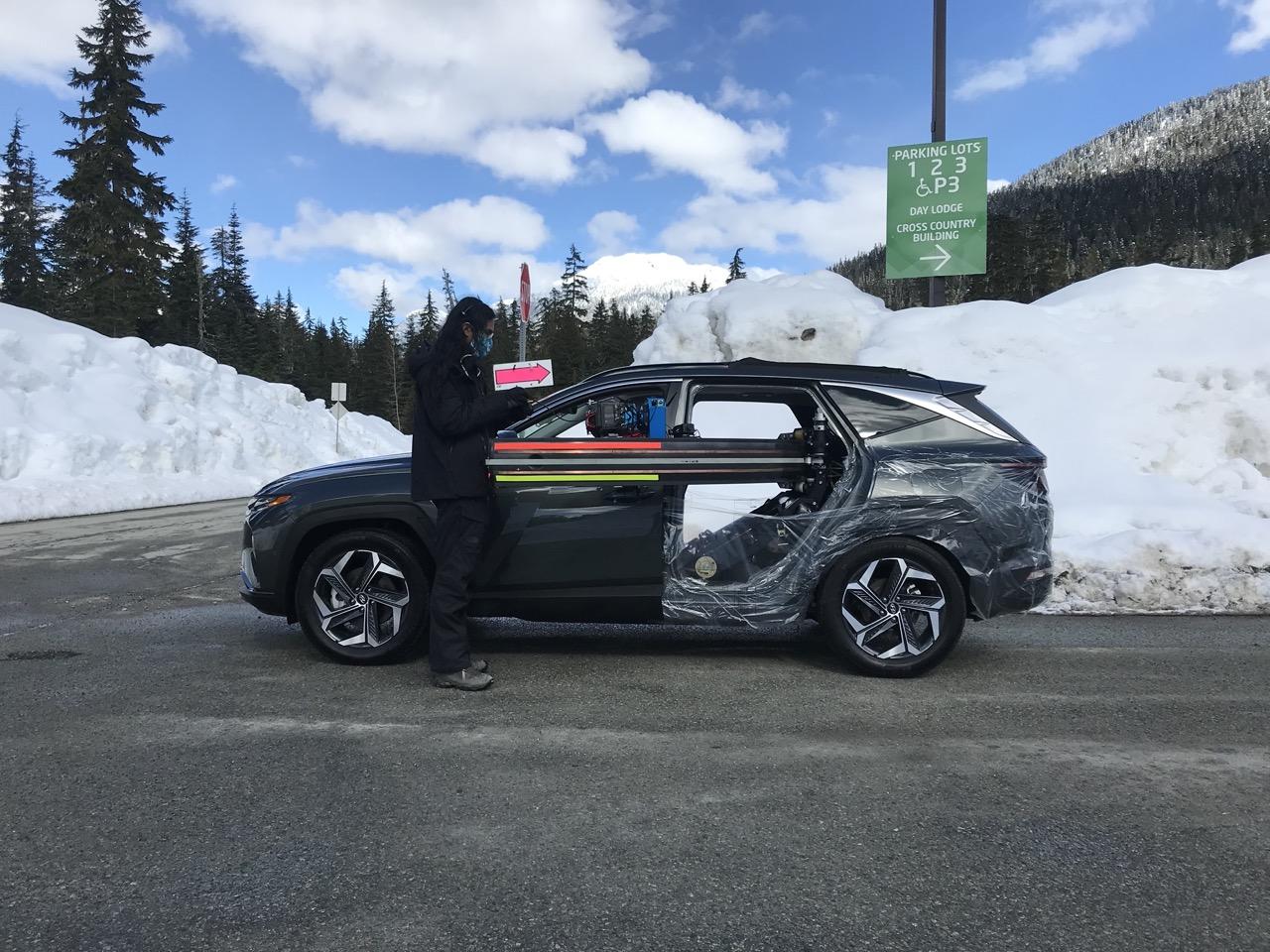 SUV parked in snowy mountain setting, person standing nearby.