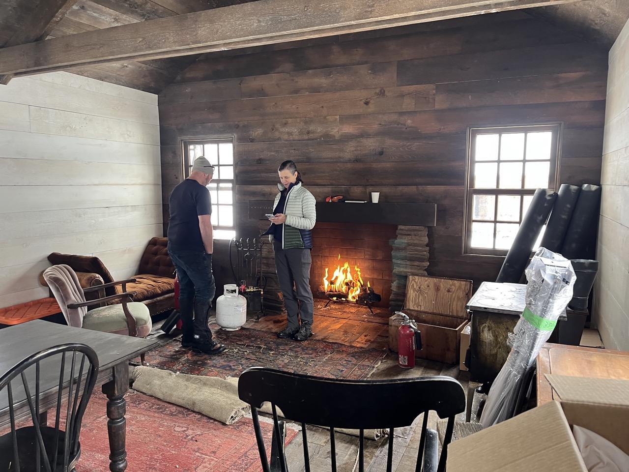 Cozy rustic room with people by a fireplace.