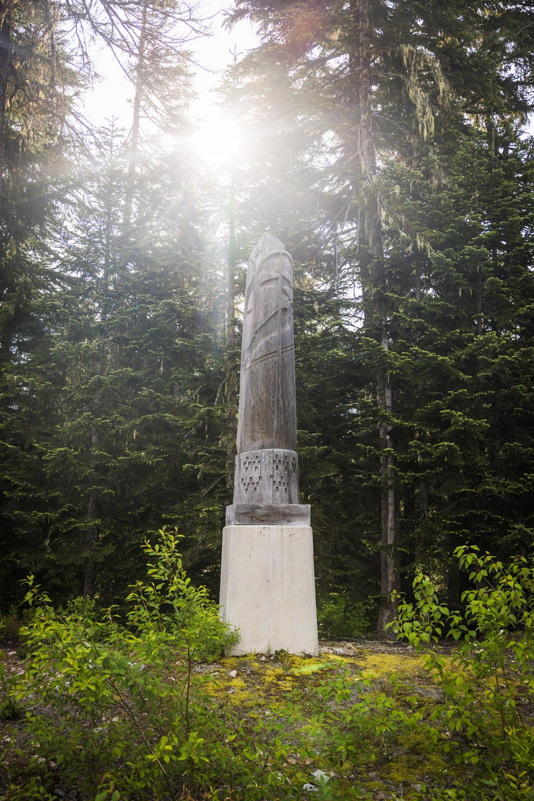 Stone monument surrounded by forest, sunlight shining through trees.