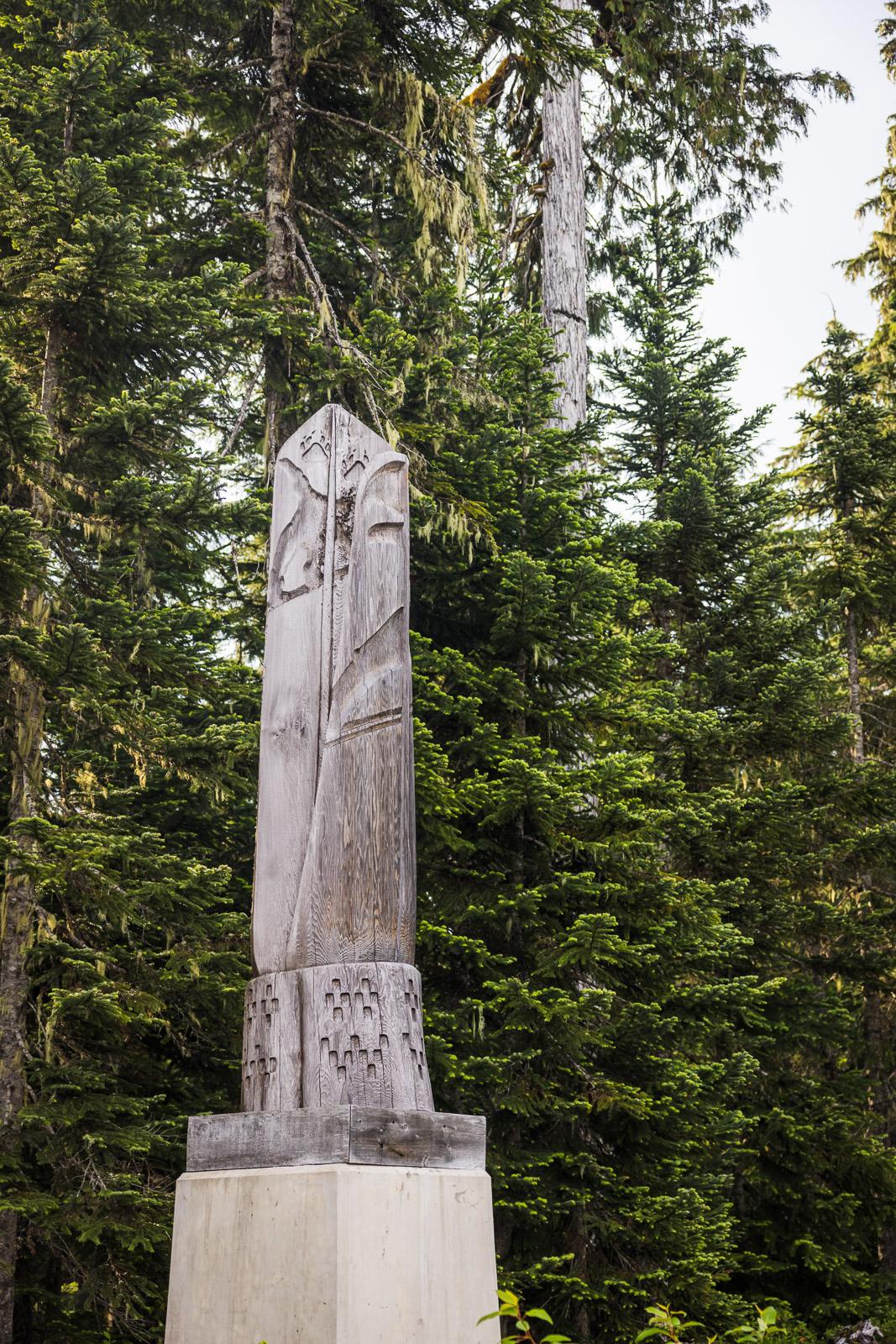 Stone monument in forest setting with tall evergreen trees. Vision Earned