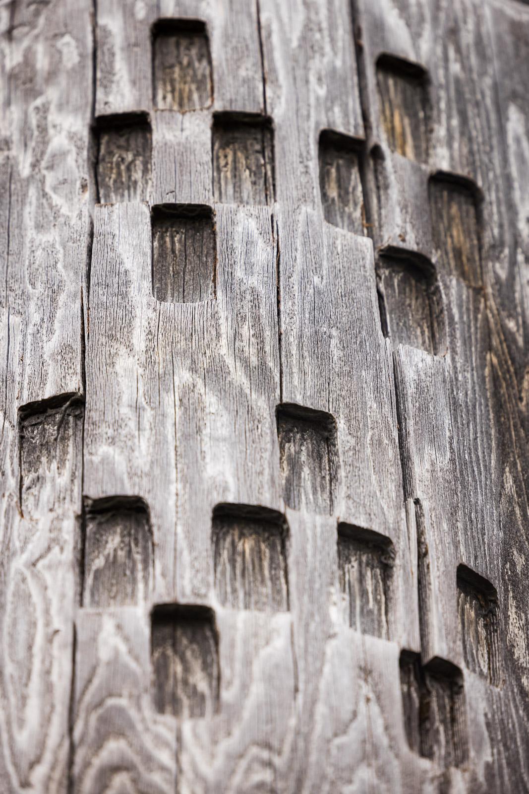 Weathered wood with square carvings forming a geometric pattern.