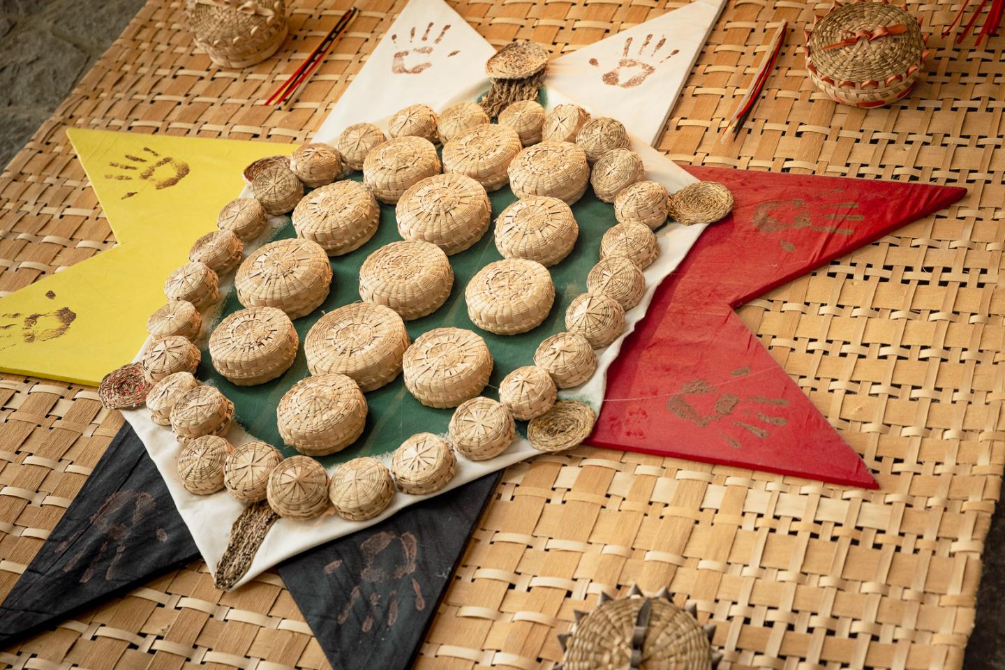 Round sesame cookies arranged on a green tray, set against a colorful woven mat.