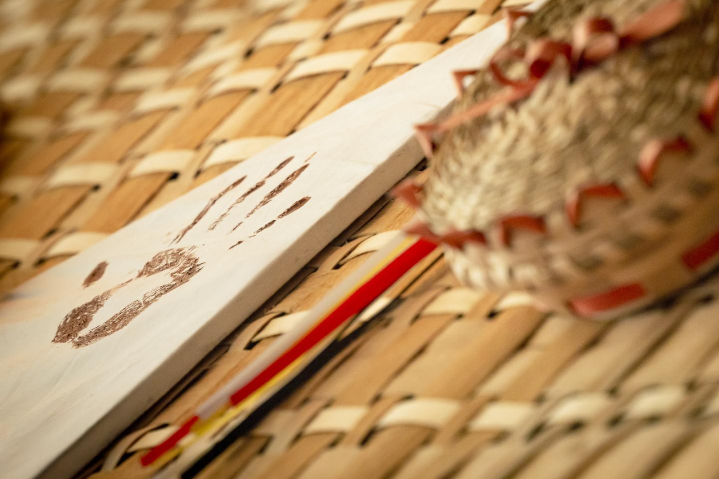 Handprint on paper, basket, and pencil on woven surface.