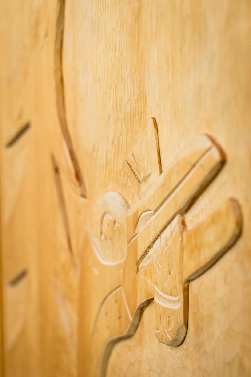 Wood carving of abstract shapes and lines in light brown tones.