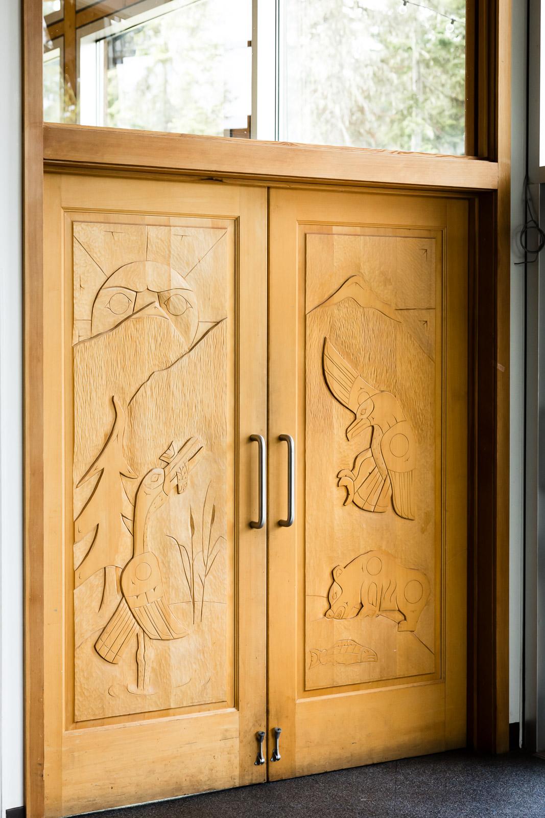 Wooden doors with carved nature scenes and metal handles.