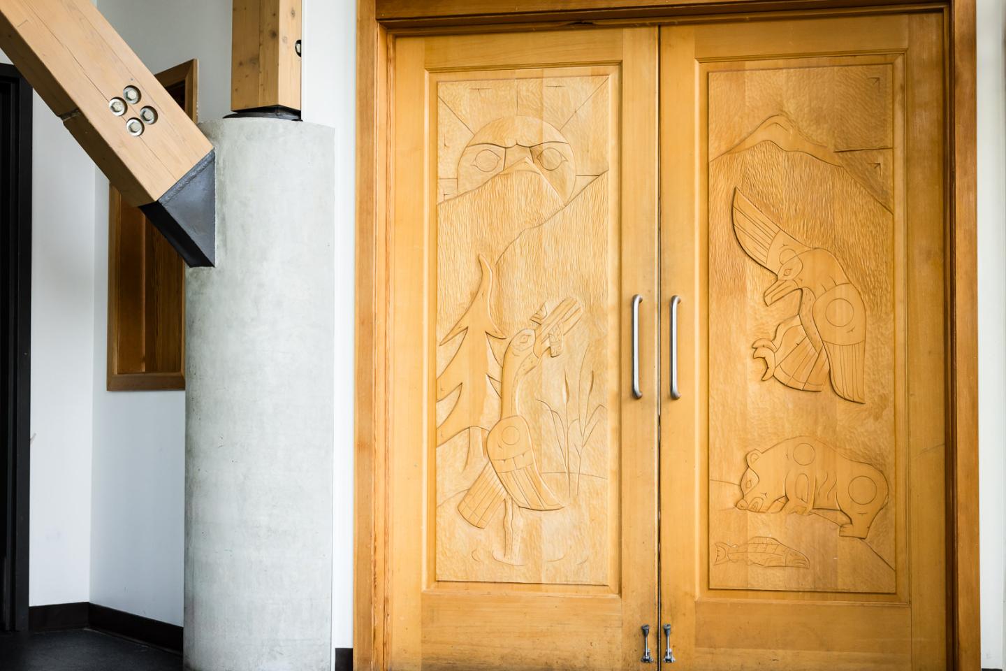 Wooden doors with intricate carved designs in a modern interior setting.