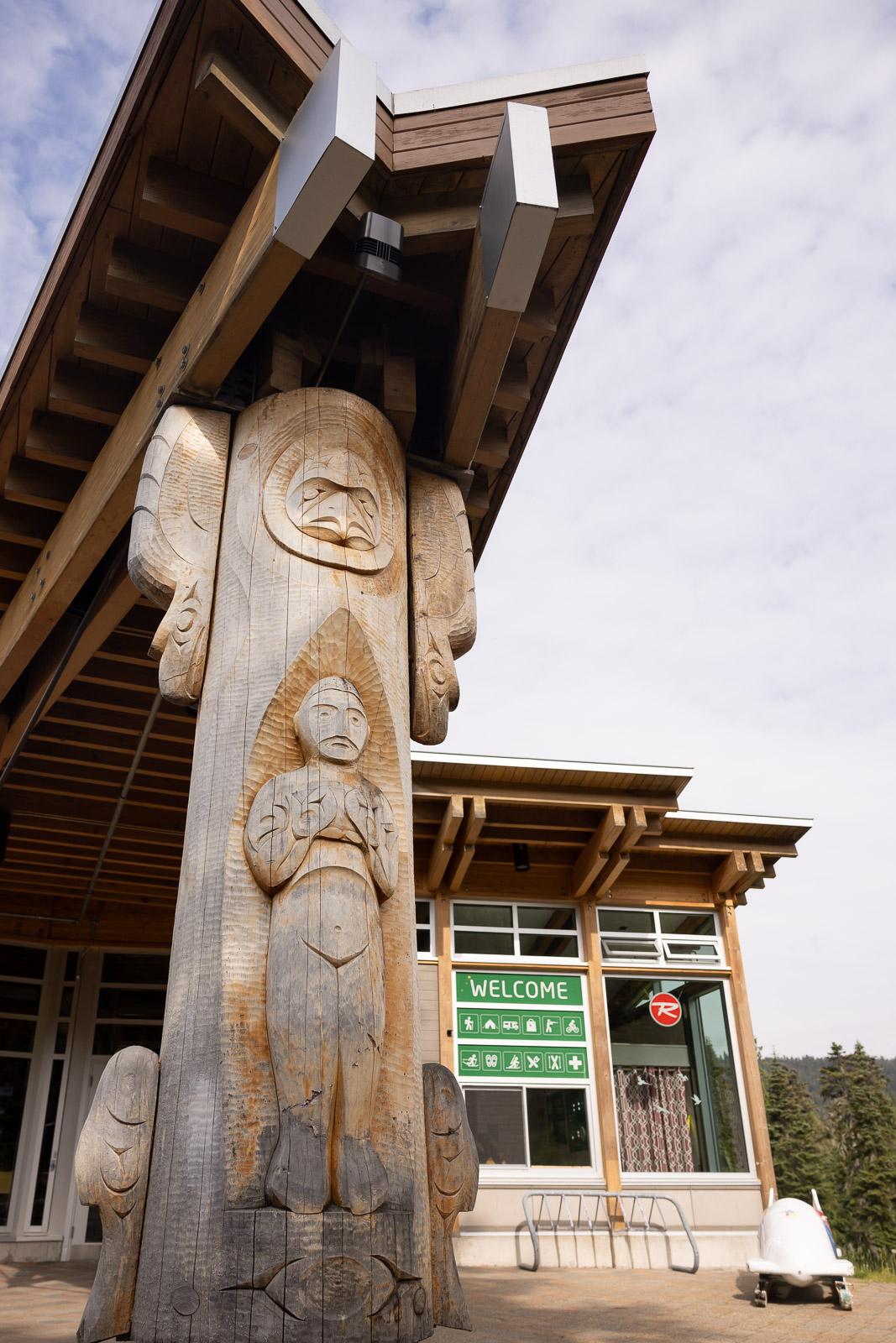 Carved wooden totem pole outside modern building.
