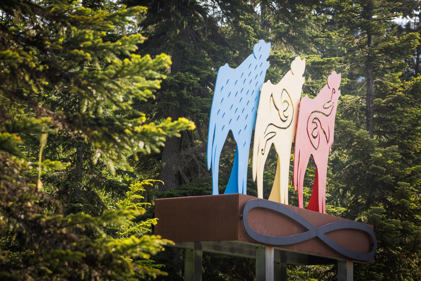 Colorful animal sculptures on pedestal, surrounded by trees.