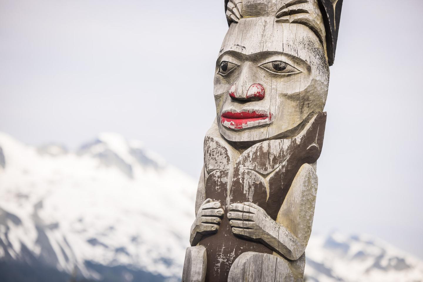 Totem pole with mountains in the background.