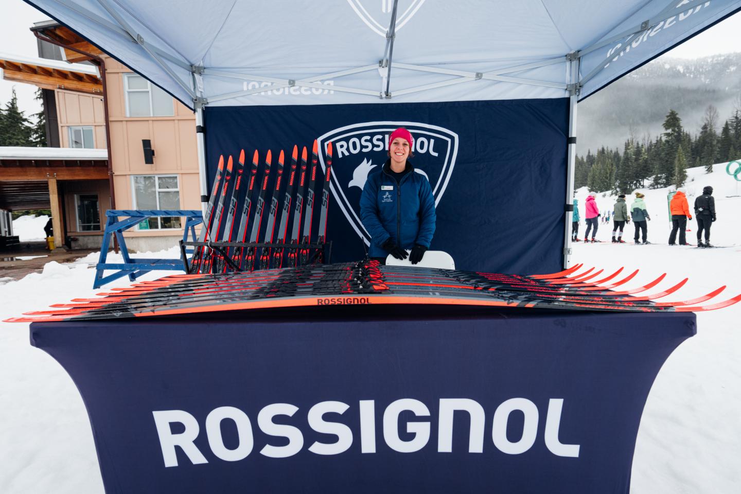 Ski rental booth with red skis displayed under a canopy in snowy setting.