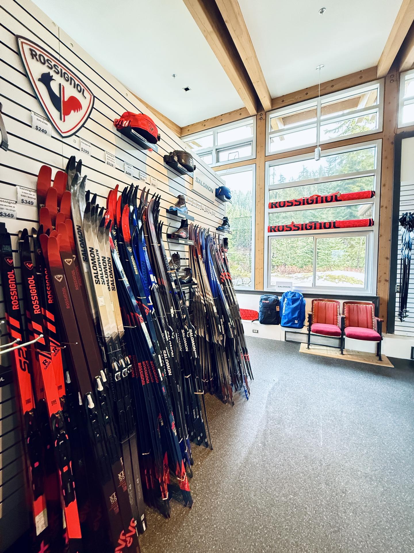 Ski shop with skis on racks, bright natural light from large windows.