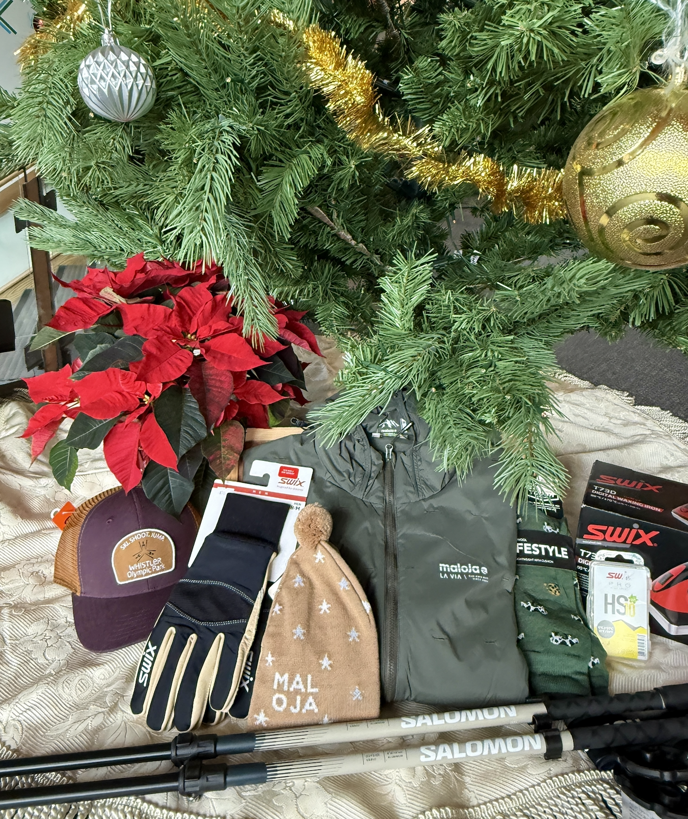 Christmas tree with gifts including clothing, gloves, and trekking poles.