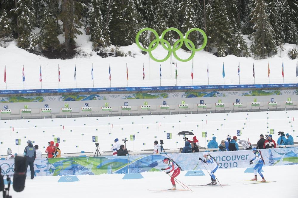 Skiers competing in snowy Olympic event with large rings above.