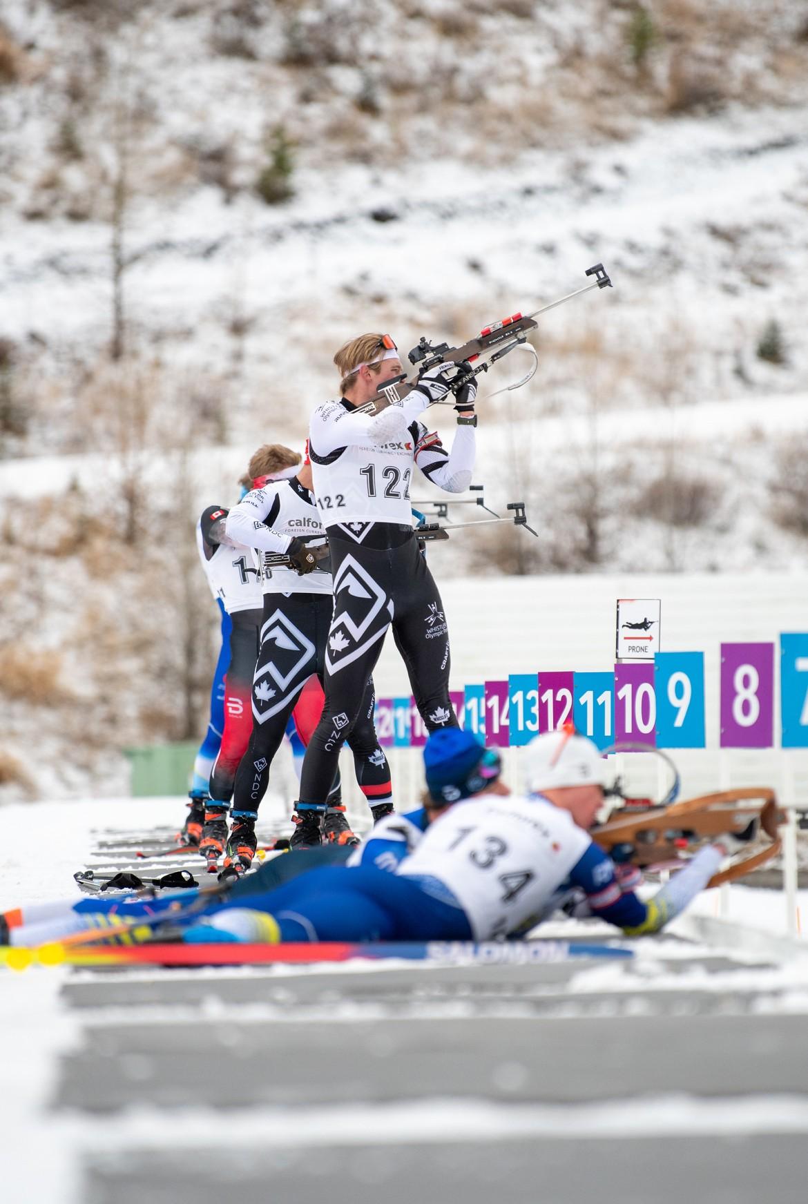 Biathletes aiming rifles at a snowy outdoor range.