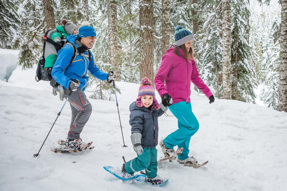 Family snowshoeing together in a snowy forest.