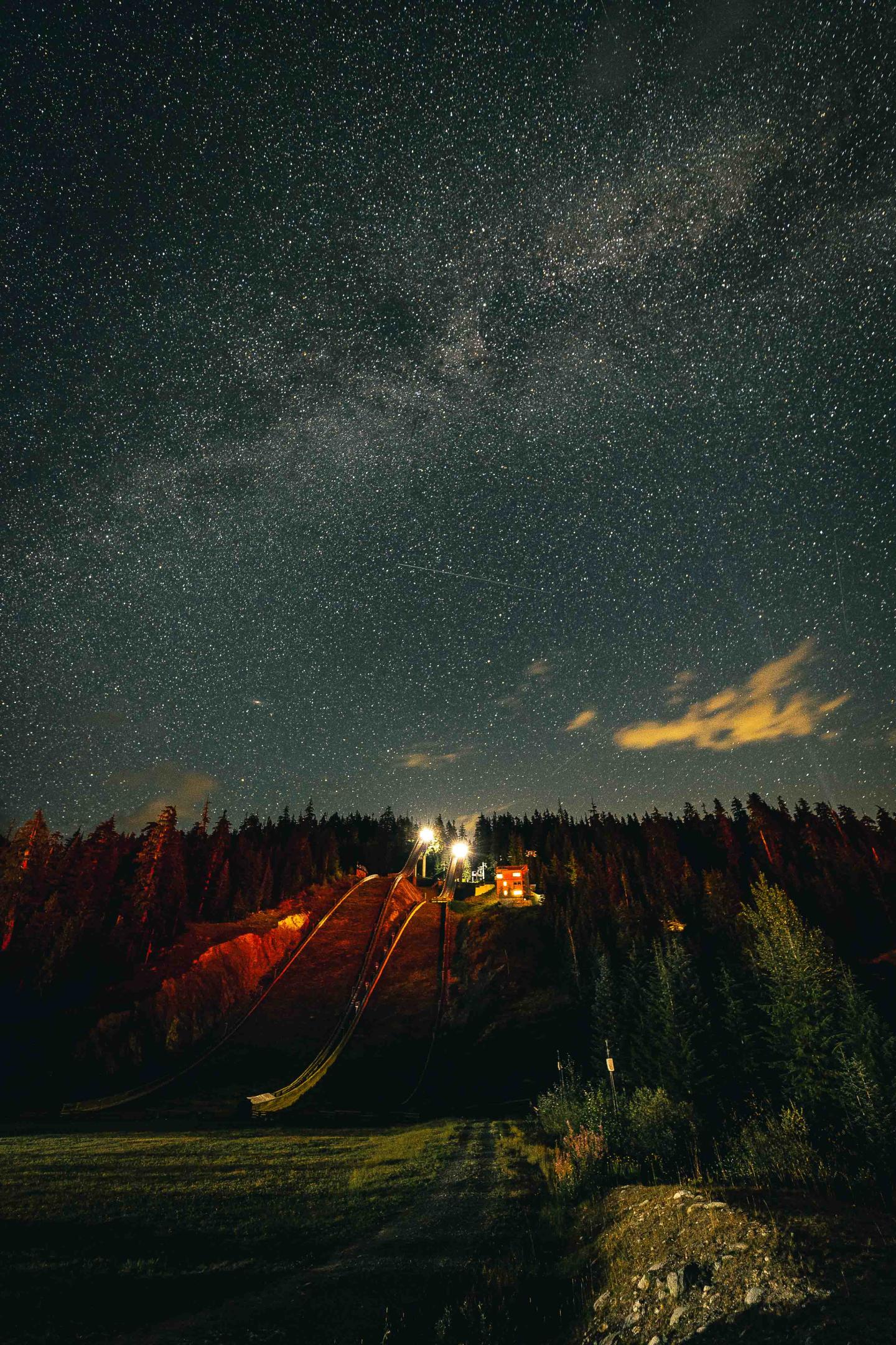  Whistler Olympic Park Starry night sky above a forested landscape with distant lights.