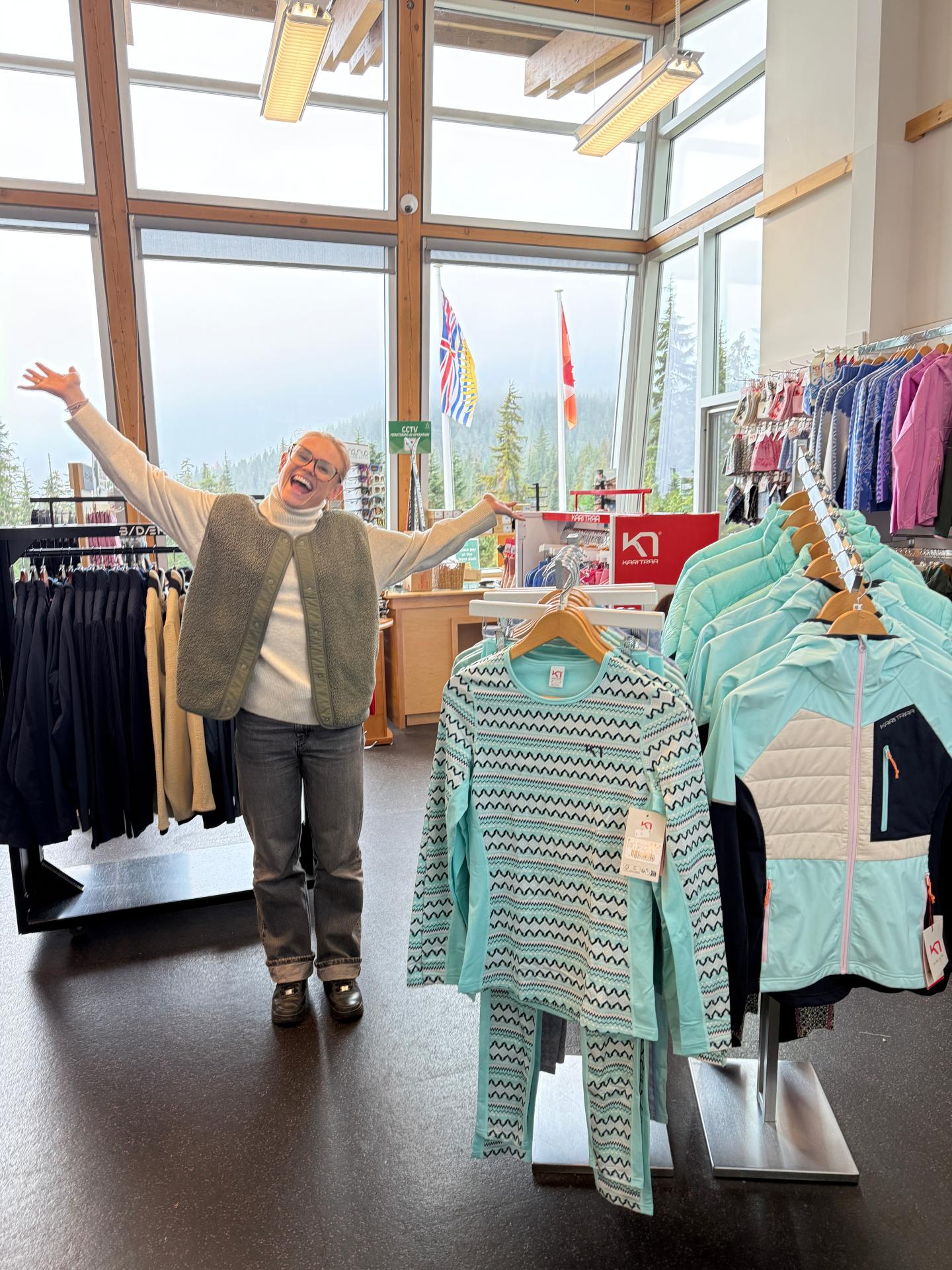 Woman in a boutique holds up a turquoise striped baby outfit.